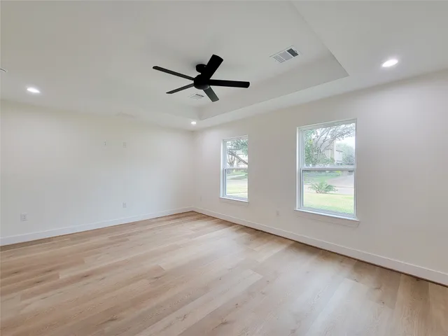 a view of an empty room with a window and wooden floor