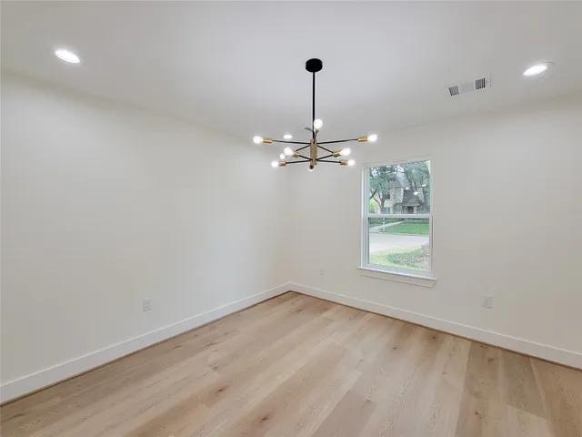 a view of an empty room with window and a kitchen
