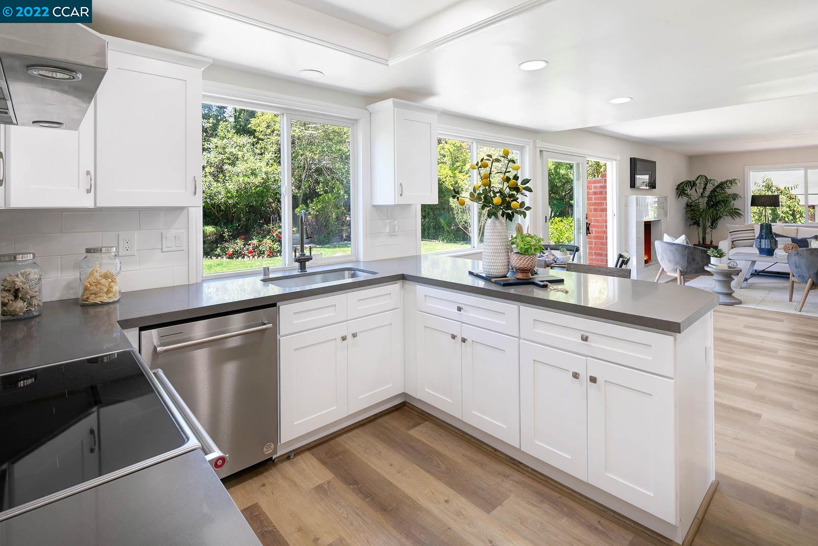 a kitchen with stainless steel appliances white cabinets a sink a stove and a window