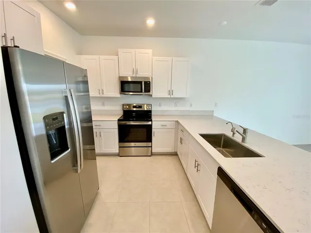 a kitchen with stainless steel appliances a refrigerator a sink a stove a microwave and a refrigerator