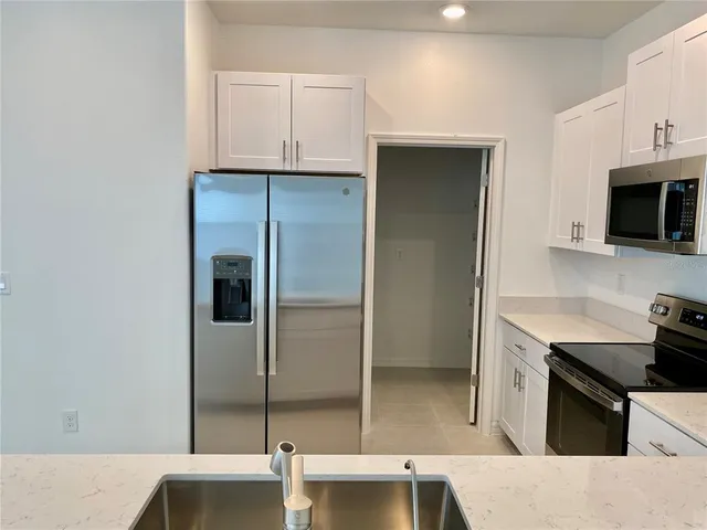 a kitchen with a sink a microwave a refrigerator and cabinets