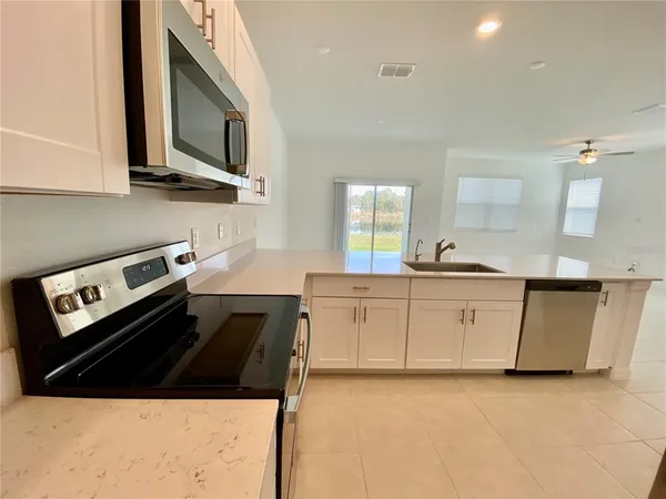 a kitchen with stainless steel appliances a stove a microwave a sink and white cabinets