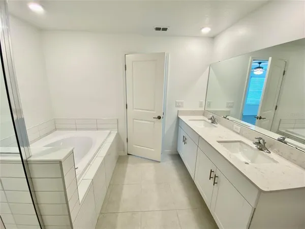 a spacious bathroom with a double vanity sink a mirror and a bathtub
