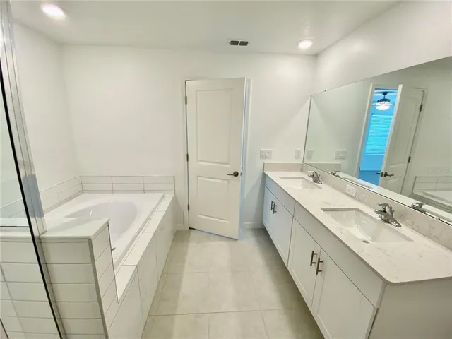a spacious bathroom with a double vanity sink a mirror and a bathtub