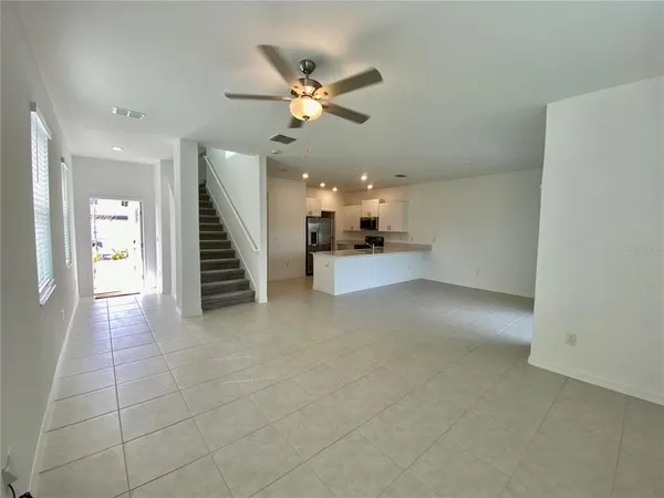 a view of a livingroom with a ceiling fan and staircase