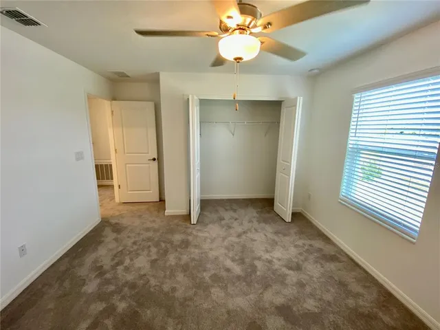an empty room with a ceiling fan and a window