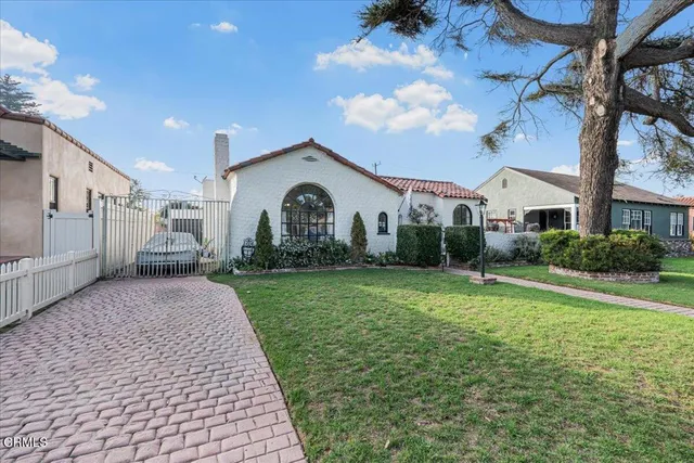 a view of a white house with a yard and table and chairs under an umbrella