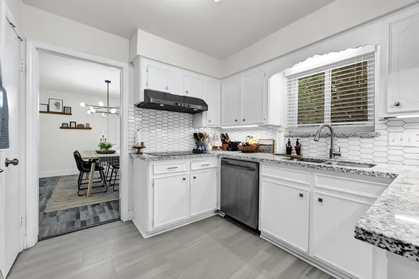 a kitchen with granite countertop white cabinets a sink a window and stainless steel appliances
