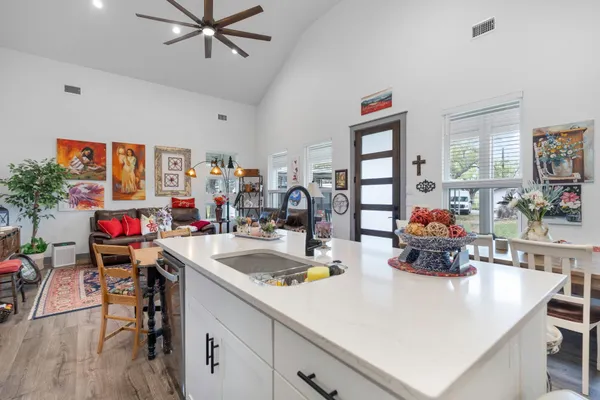 a very nice looking living room with kitchen island furniture a chandelier and a wooden floor