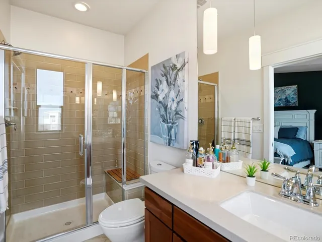 a bathroom with a granite countertop sink a toilet a mirror and shower