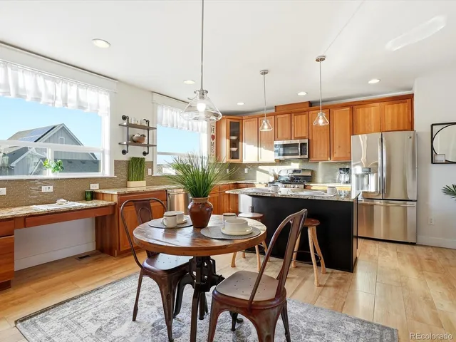 a kitchen with a refrigerator a stove a sink a dining table and chairs