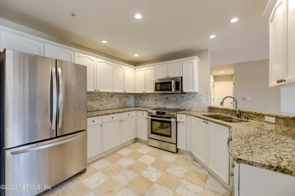 a kitchen with granite countertop a refrigerator stove top oven and sink