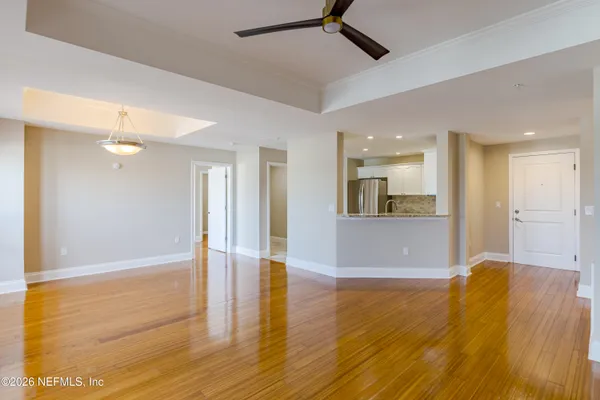 a view of a big room with wooden floor and a kitchen