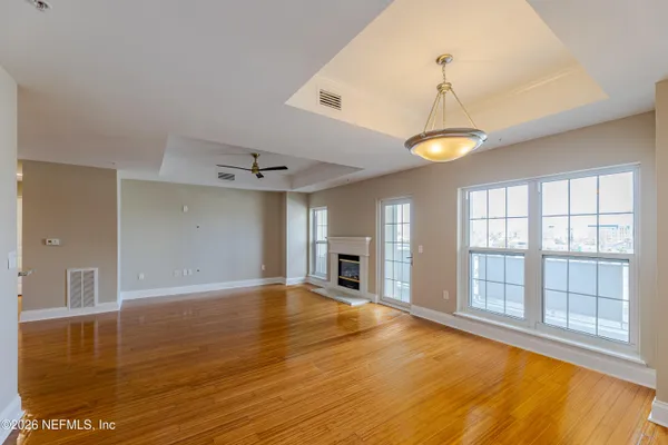 a view of an empty room with window and wooden floor