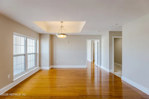 a view of an empty room with window and wooden floor