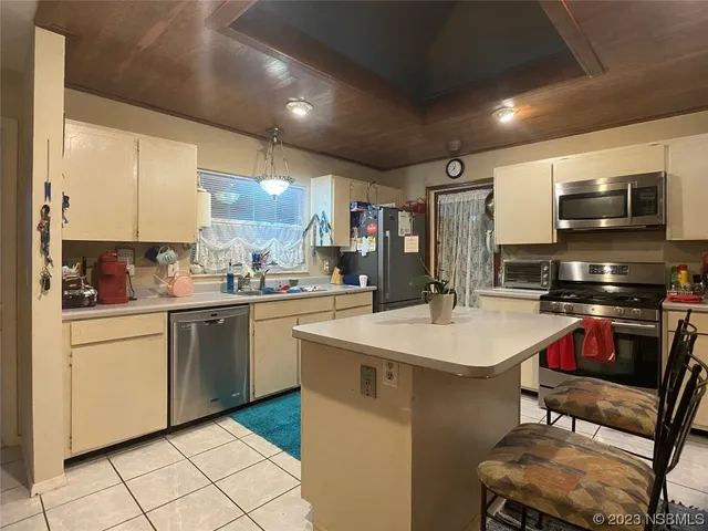 a kitchen with stainless steel appliances a stove a sink dishwasher a refrigerator and white cabinets with wooden floor