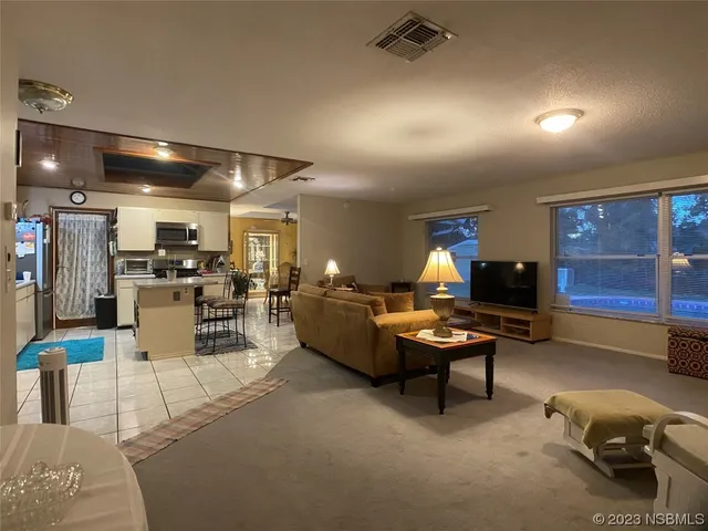 a living room with furniture a table and kitchen view