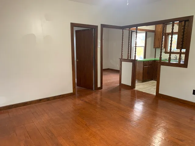 a view of an empty room with a window and wooden floor