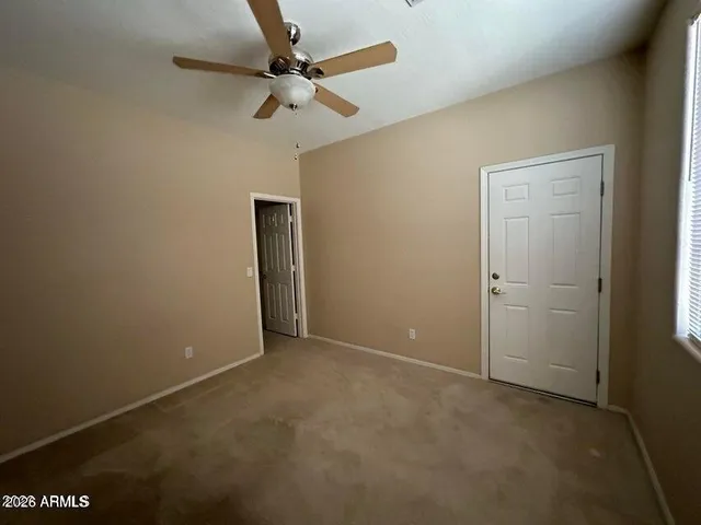 an empty room with a ceiling fan and carpet