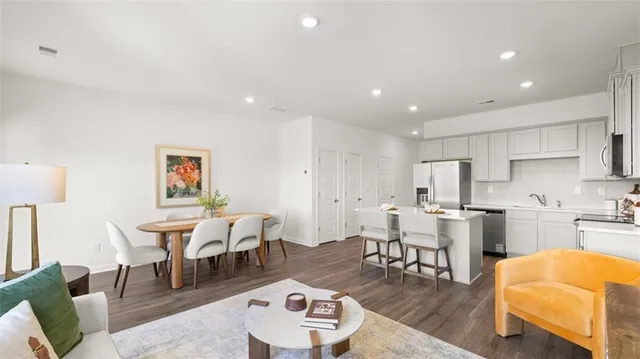 a living room with stainless steel appliances furniture and a kitchen view