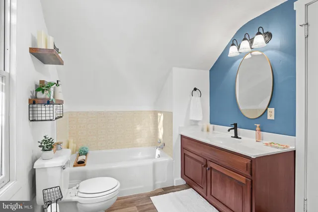 a bathroom with a toilet a sink a tub and mirror