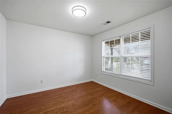 a view of an empty room with wooden floor and closet