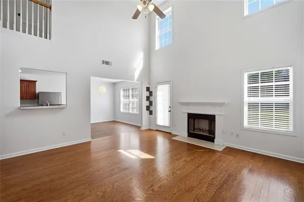 a view of an empty room with wooden floor fireplace and a window