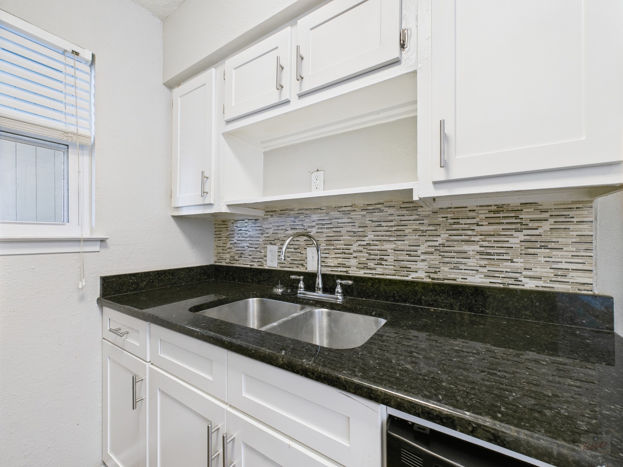 2401 Manor Road, Unit 136 Austin, TX 78722 - Photo 3 of 12 a kitchen with granite countertop a sink and cabinets