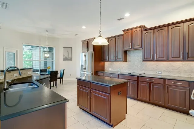 a kitchen with kitchen island granite countertop a stove top oven a sink dishwasher and cabinets with wooden floor