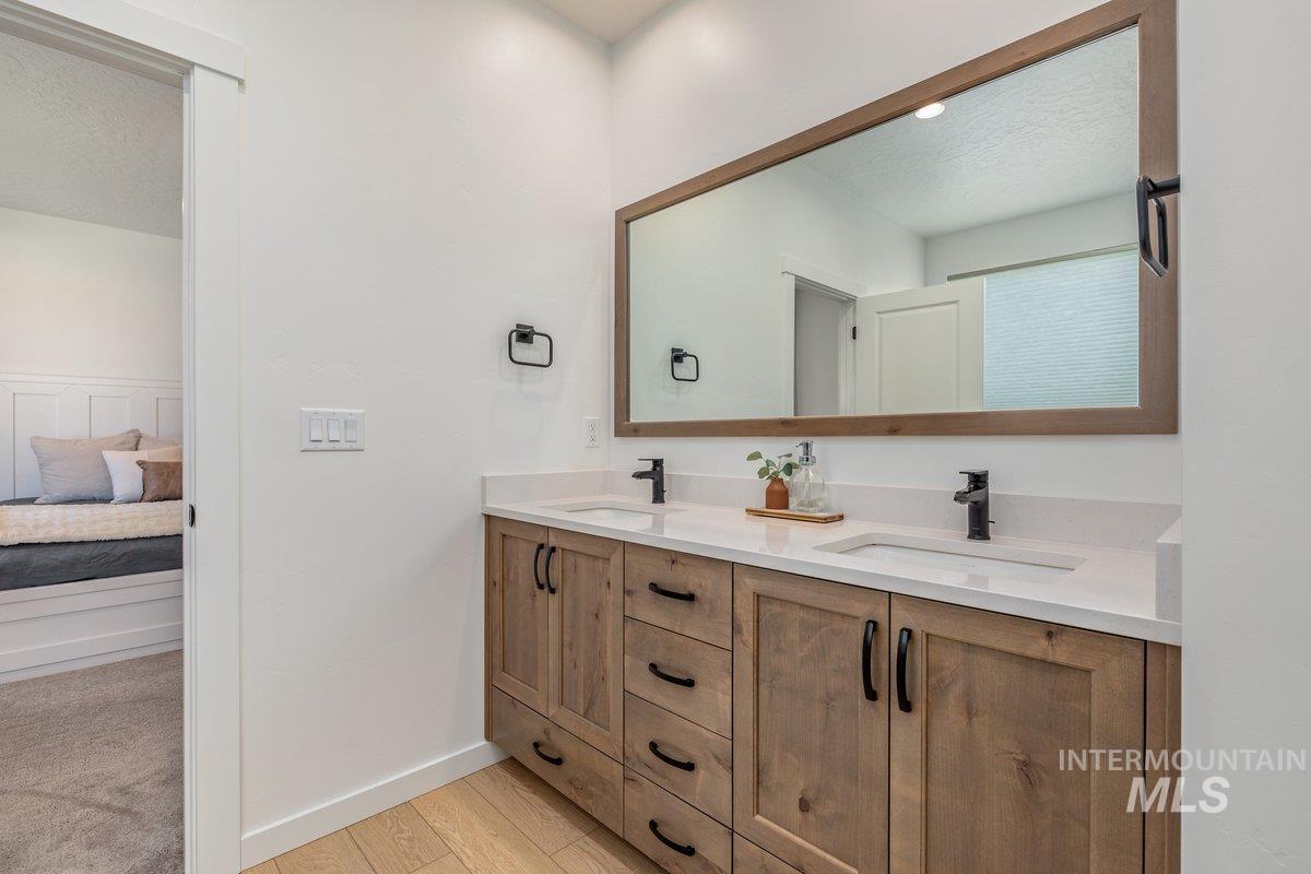 1380 West Chilitna Street Meridian, ID 83642 - Photo 28 of 50 Double vanity featuring light wood-finish cabinetry, integrated sinks, white countertops, and matte black fixtures