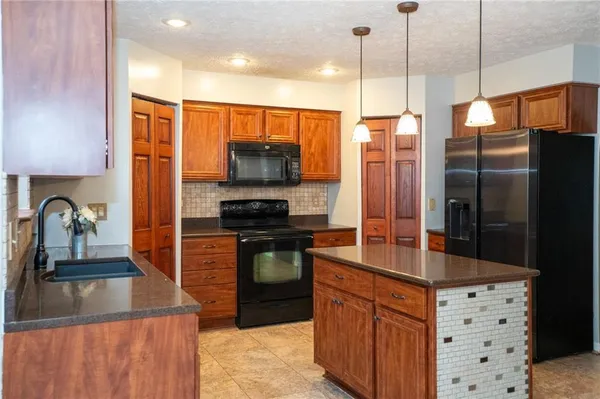 a kitchen with stainless steel appliances granite countertop a refrigerator a sink and a stove