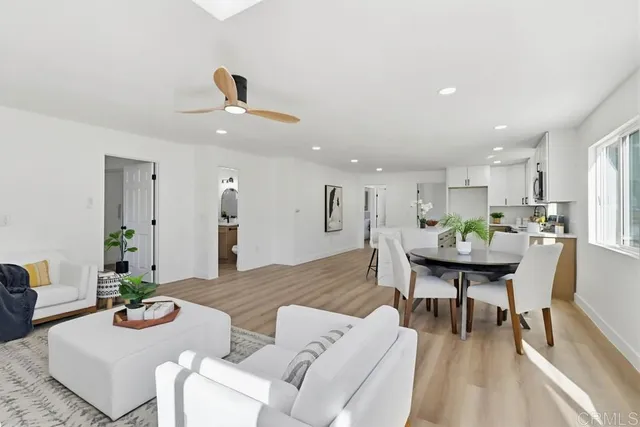 a living room with furniture kitchen view and a wooden floor