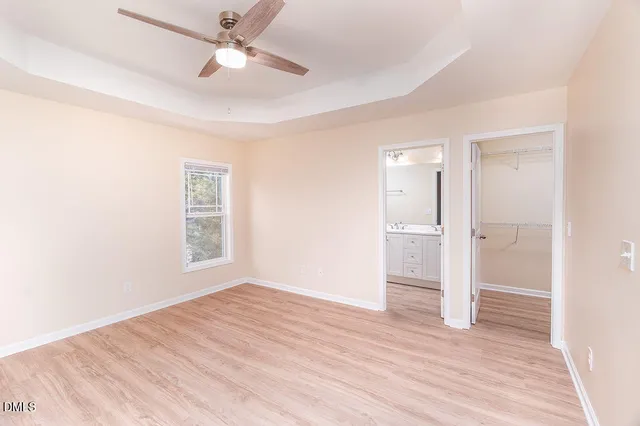 a view of empty room with wooden floor and fan
