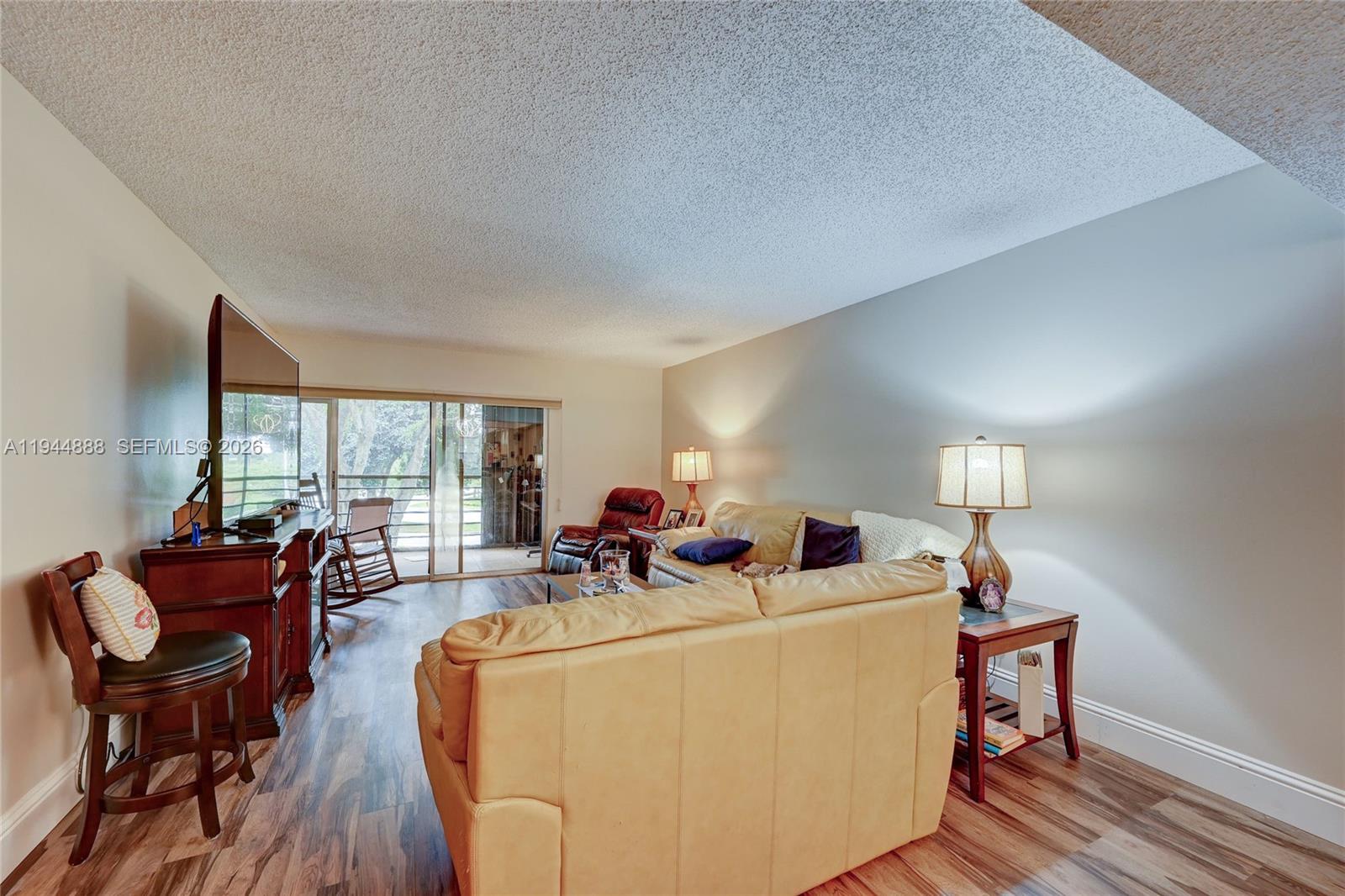 23344 Carolwood Lane, Unit 303 Boca Raton, FL 33428 - Photo 11 of 26 a living room with furniture a window and a flat screen tv