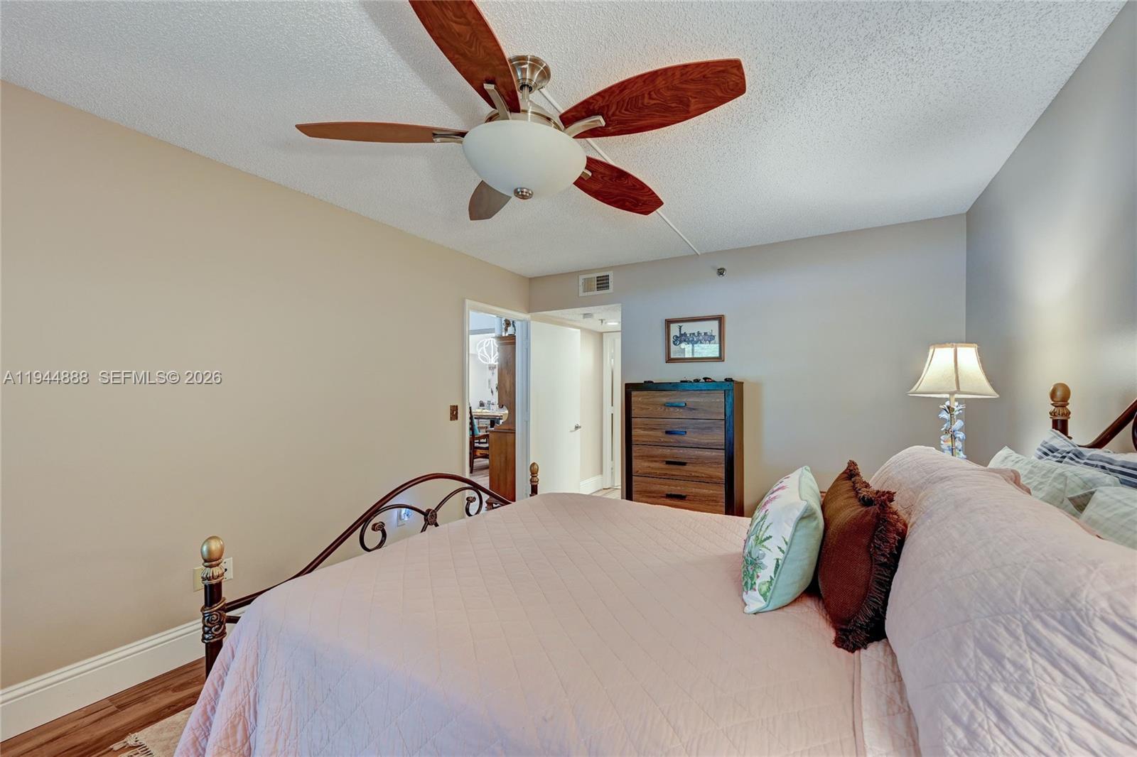 23344 Carolwood Lane, Unit 303 Boca Raton, FL 33428 - Photo 14 of 26 a bedroom with a bed and a chandelier