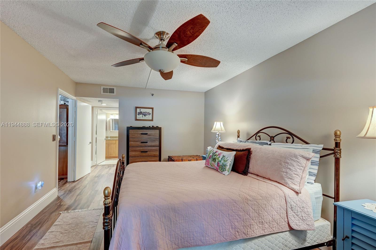 23344 Carolwood Lane, Unit 303 Boca Raton, FL 33428 - Photo 15 of 26 a bedroom with a bed and a chandelier