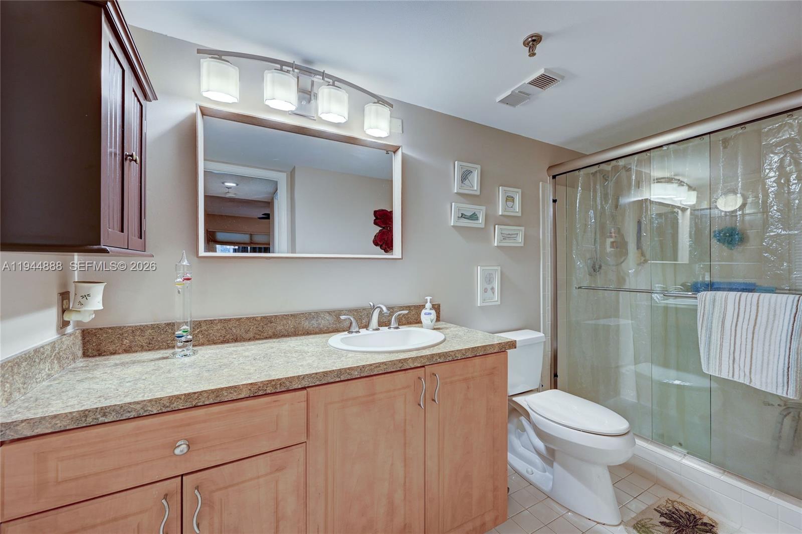 23344 Carolwood Lane, Unit 303 Boca Raton, FL 33428 - Photo 16 of 26 a bathroom with a granite countertop sink mirror vanity and toilet
