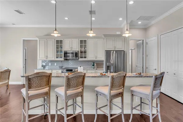 a kitchen with stainless steel appliances kitchen island granite countertop a dining table chairs refrigerator and microwave
