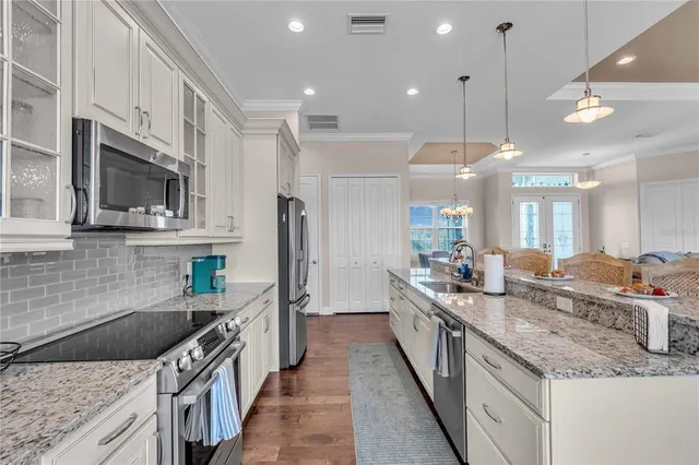 a kitchen with stainless steel appliances granite countertop a sink a stove and a wooden floors