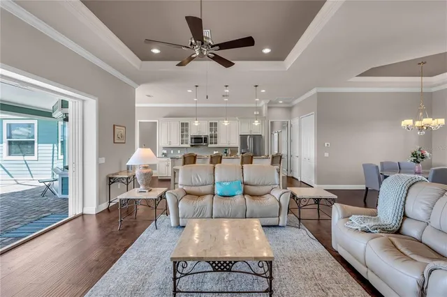 a living room with furniture kitchen view and a chandelier