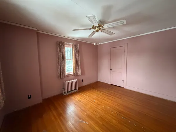 a view of an empty room with wooden floor and a window
