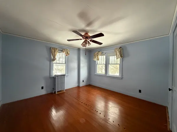 an empty room with windows and ceiling fan