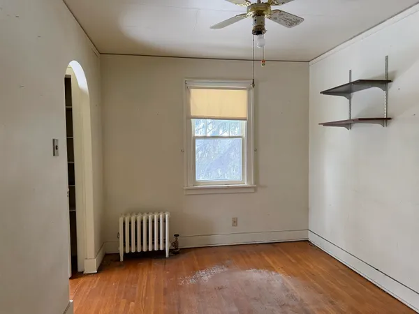 a view of empty room with a window and wooden floor