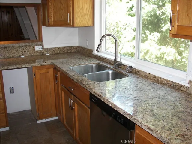 a kitchen with granite countertop a sink a counter and cabinets