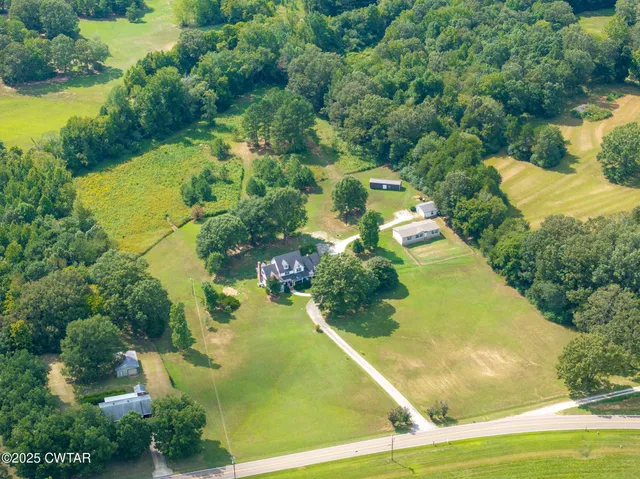 an aerial view of residential houses with outdoor space and trees all around