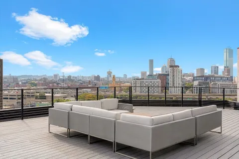 a view of a roof deck with couches and potted plants