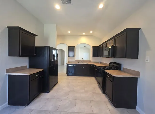 a large kitchen with a large counter top stainless steel appliances and a sink