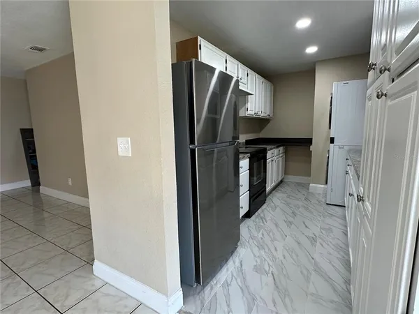 a view of a refrigerator in kitchen and an empty room