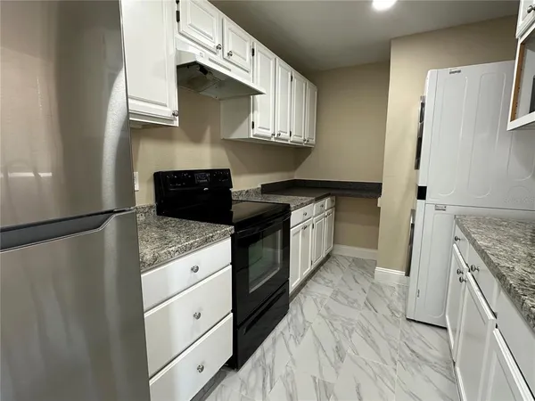 a kitchen with granite countertop a sink stove and refrigerator