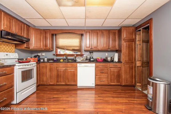a kitchen with granite countertop wooden floors stainless steel appliances a sink and cabinets